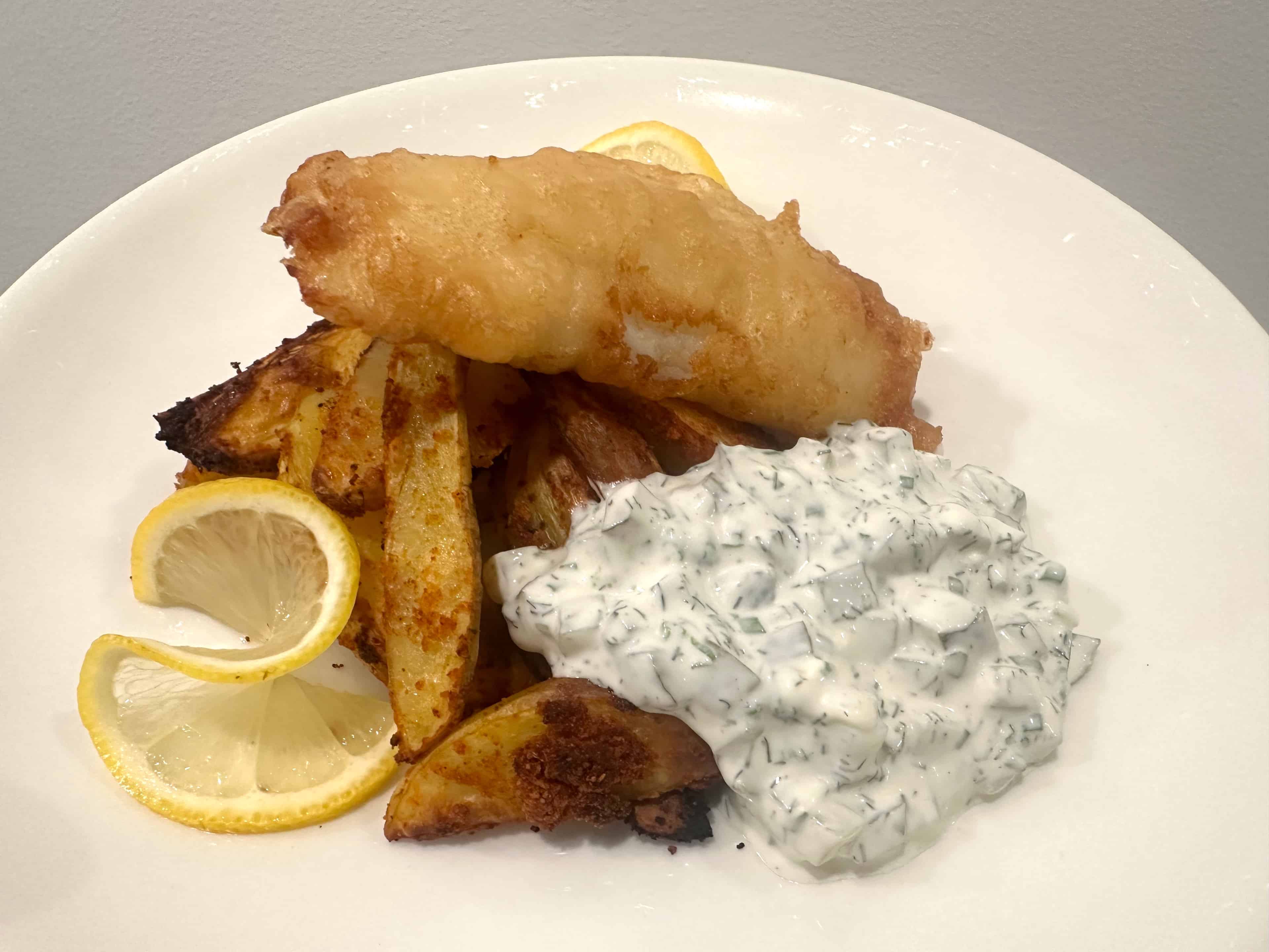 Fish & Chips annos lohkoperunoiden ja tartar -kastikkeen kanssa Fish & chips annos tarjoaa houkuttelevan yhdistelmän rapeutta, tuoreutta ja tasapainoisia makuja.